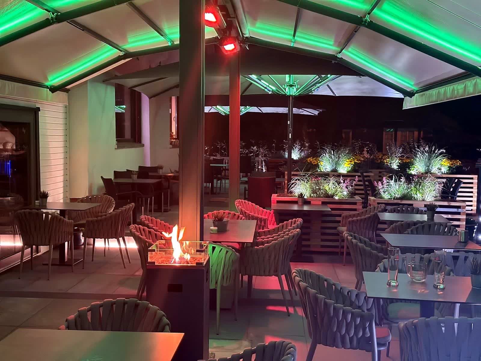 Überdachte Terrasse mit Feuerstelle am Abend